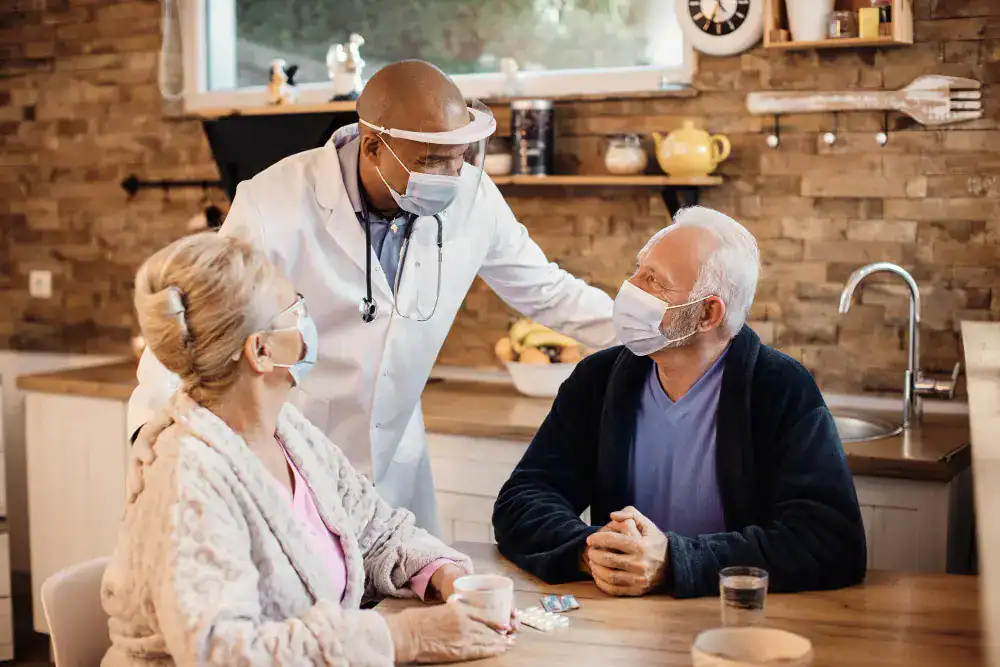 Doctor wearing face shield and mask speaking with elderly patients at home