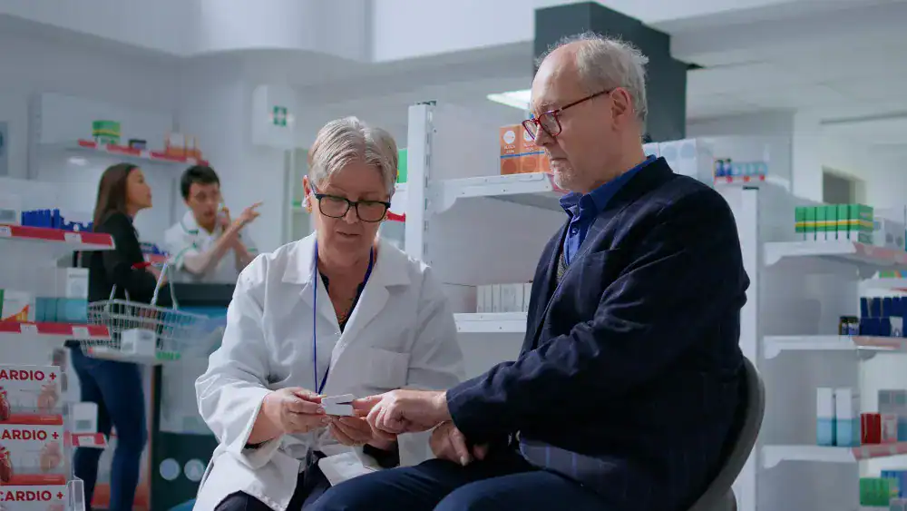 Female healthcare worker explaining medication details to senior patient in clinic