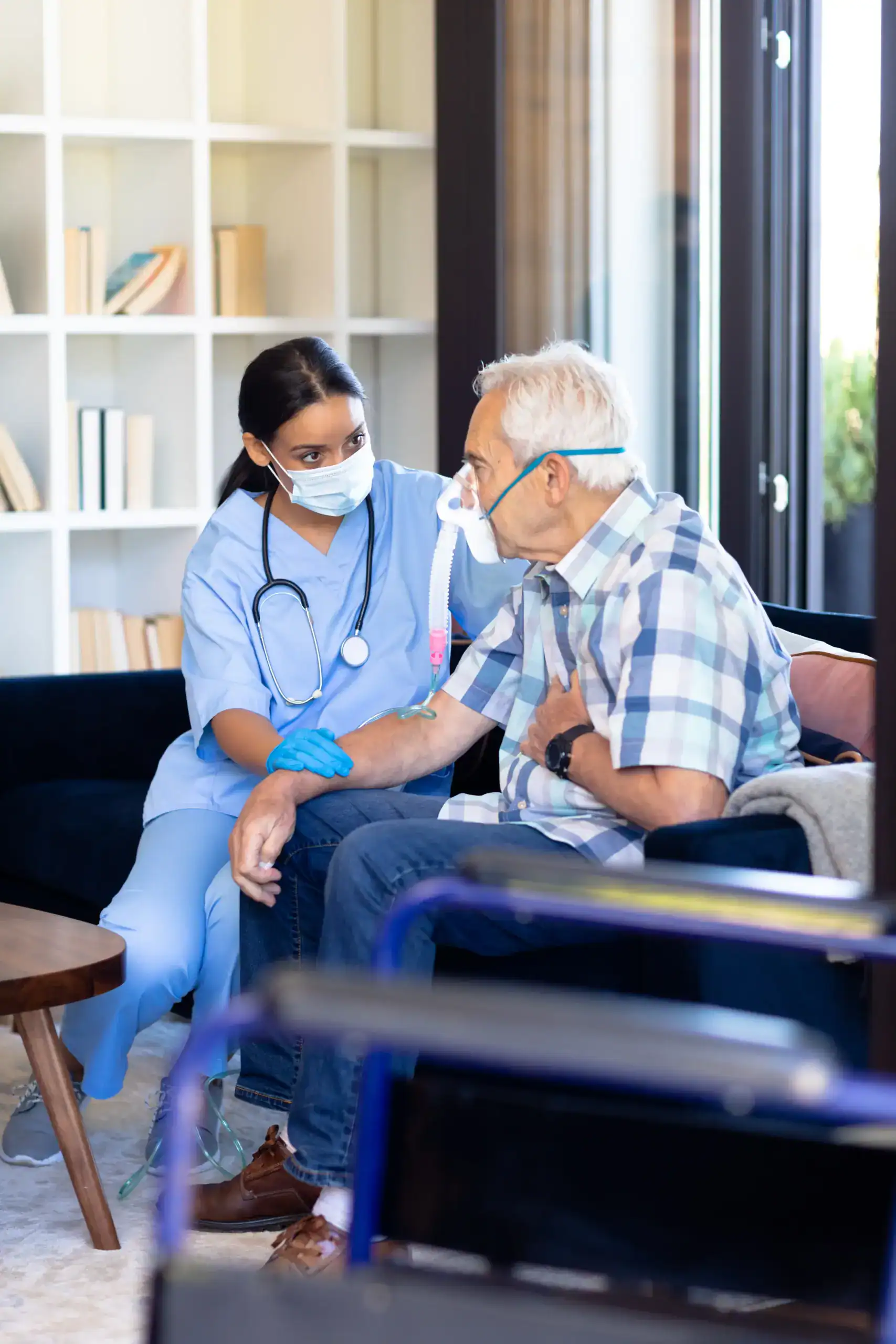 Nurse assisting an elderly patient using an oxygen mask during a home healthcare visit